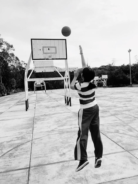 Photo rear view of woman playing basketball on court