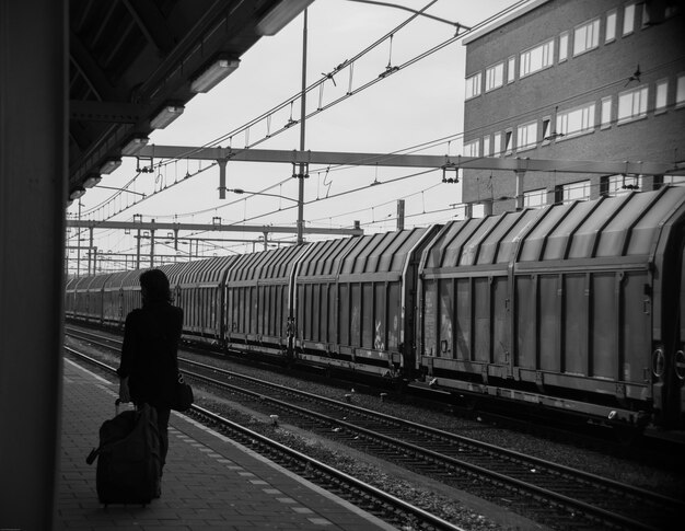 Foto vista posteriore di una donna sulla piattaforma della stazione ferroviaria in città