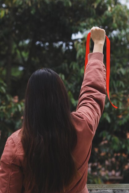 Photo rear view of woman raising red ribbon for aids awareness