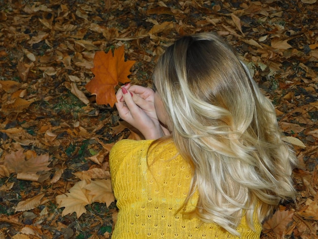 Photo rear view of woman relaxing leaves covered field during autumn