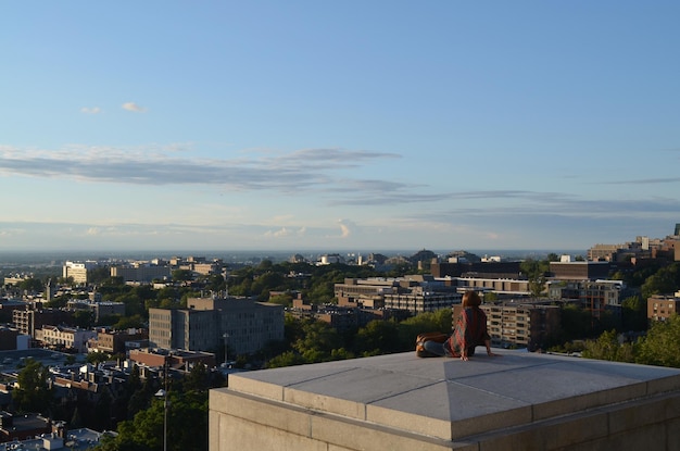 Rear view of woman relaxing on terrace against cityscape