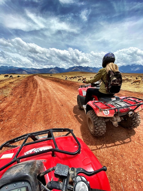 Photo rear view of woman riding quadbike on dirt road