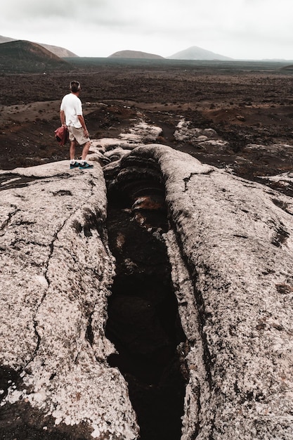 Photo rear view of woman on rock by landscape against sky