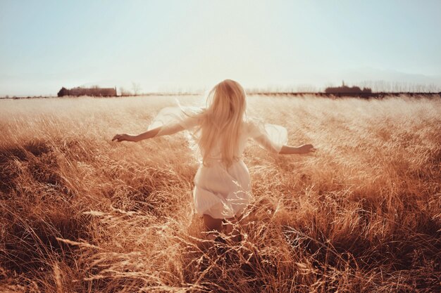 Photo rear view of woman running on field against sky