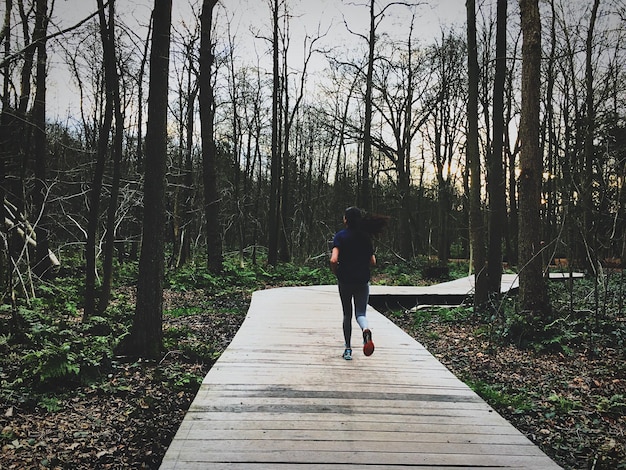 Rear view of woman running on forest