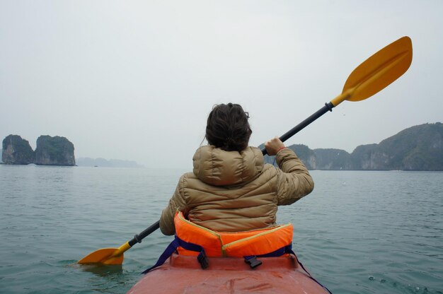 Foto vista posteriore di una donna in barca a vela nel lago