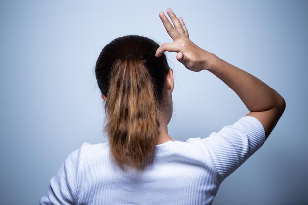 Foto vista posteriore di una donna che si gratta la testa mentre si trova sullo sfondo bianco