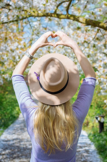 Foto vista posteriore di una donna che modella un cuore con le mani