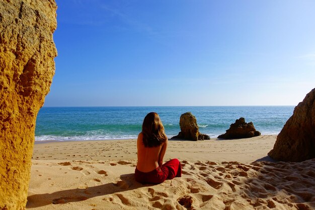 Rear view of woman sitting on beach