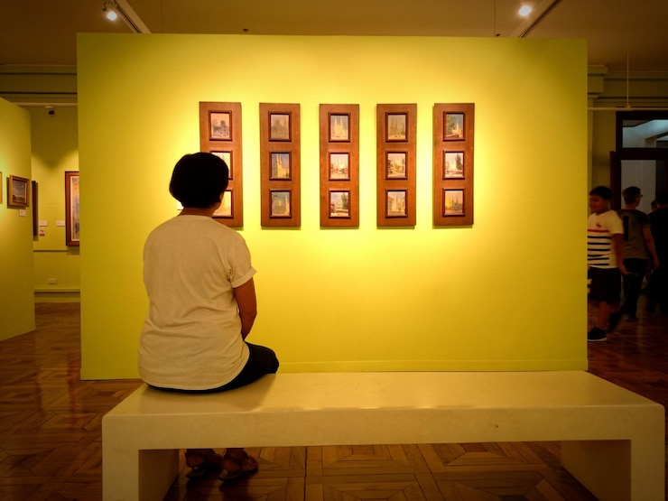 Photo 그림 프레임 을 가진 벽 에 맞대고 벤치 에 앉아 있는 여자 의 뒷면