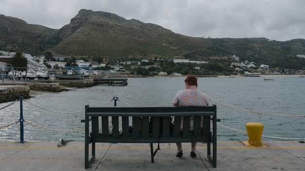 Foto vista posteriore di una donna seduta su una panchina vicino al mare
