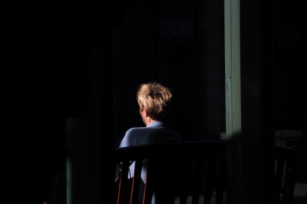 rear view of woman sitting on bench in darkroom