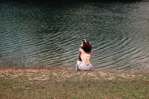 Rear view of woman sitting by lake