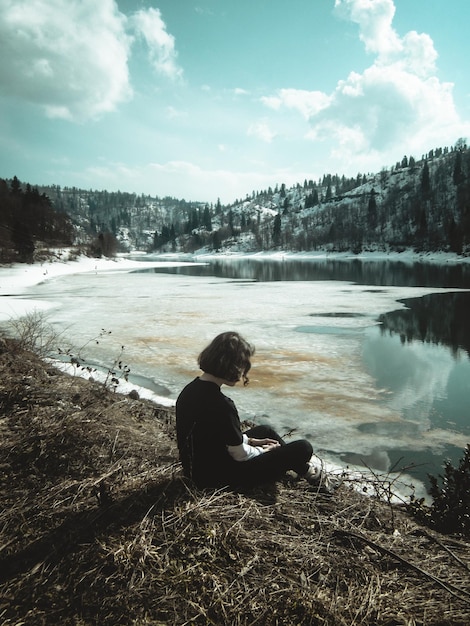 Photo rear view of woman sitting by lake