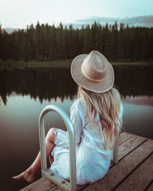 Photo rear view of woman sitting by lake