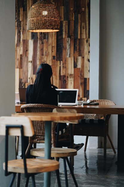 Photo rear view of woman sitting on chair at table