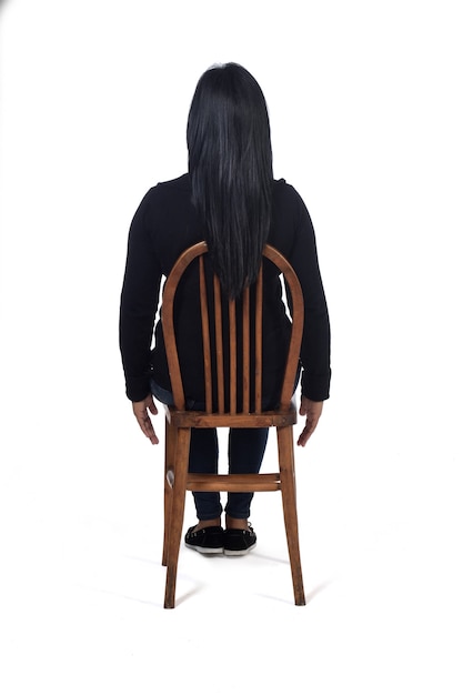 Вид сзади женщины, сидящей на стуле на белом фоне,