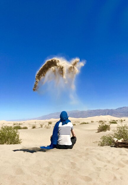 Rear view of woman sitting on desert