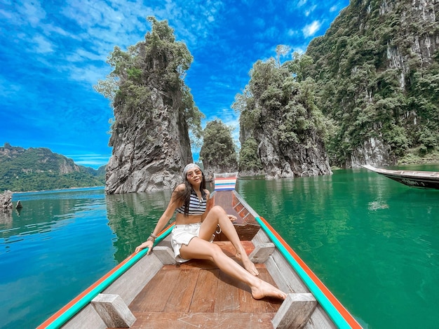 Rear view of woman sitting on pier over lake against sky