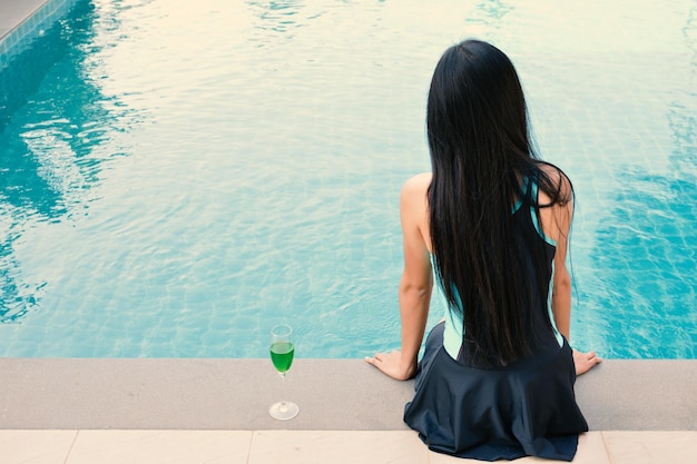 Photo rear view of woman sitting at poolside