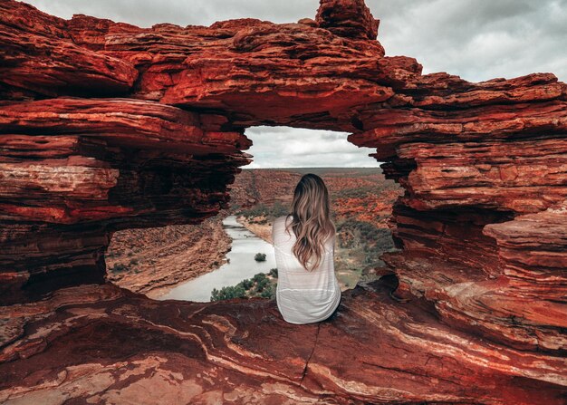 Foto vista posteriore di una donna seduta su una formazione rocciosa