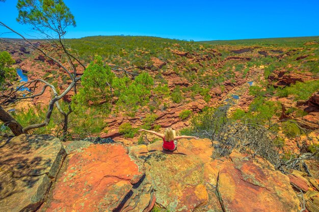 Foto vista posteriore di una donna seduta su una roccia al parco nazionale di kalbarri