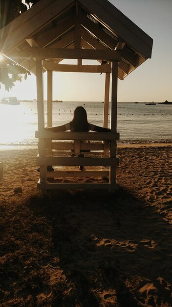 Photo rear view of woman sitting in shed at beach