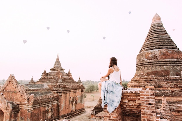 明るい空を背景に寺院に座っている女性の後ろの景色