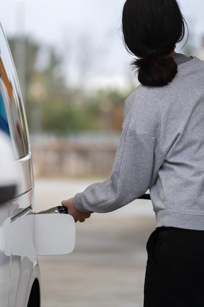 Foto vista posteriore di una donna in abiti sportivi che rifornisce di carburante l'auto