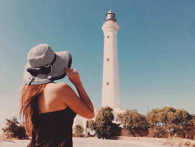 晴れた空に背を向けて立っている女性の後ろの景色
