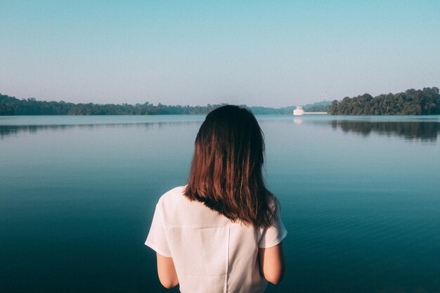 湖の向こうに立っている女性の後ろの景色