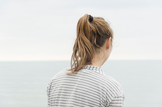 Foto vista posteriore di una donna in piedi contro il mare