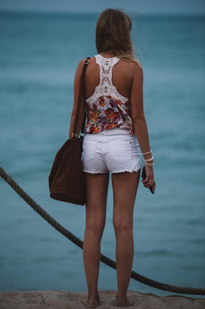 Foto vista posteriore di una donna in piedi contro il mare