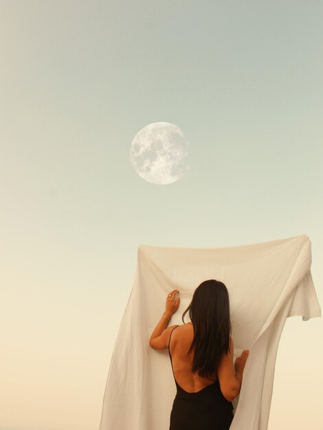 Rear view of woman standing against sky