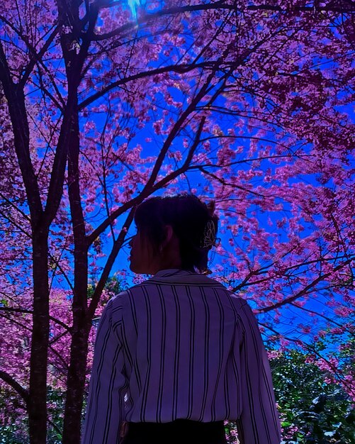 Rear view of woman standing against trees