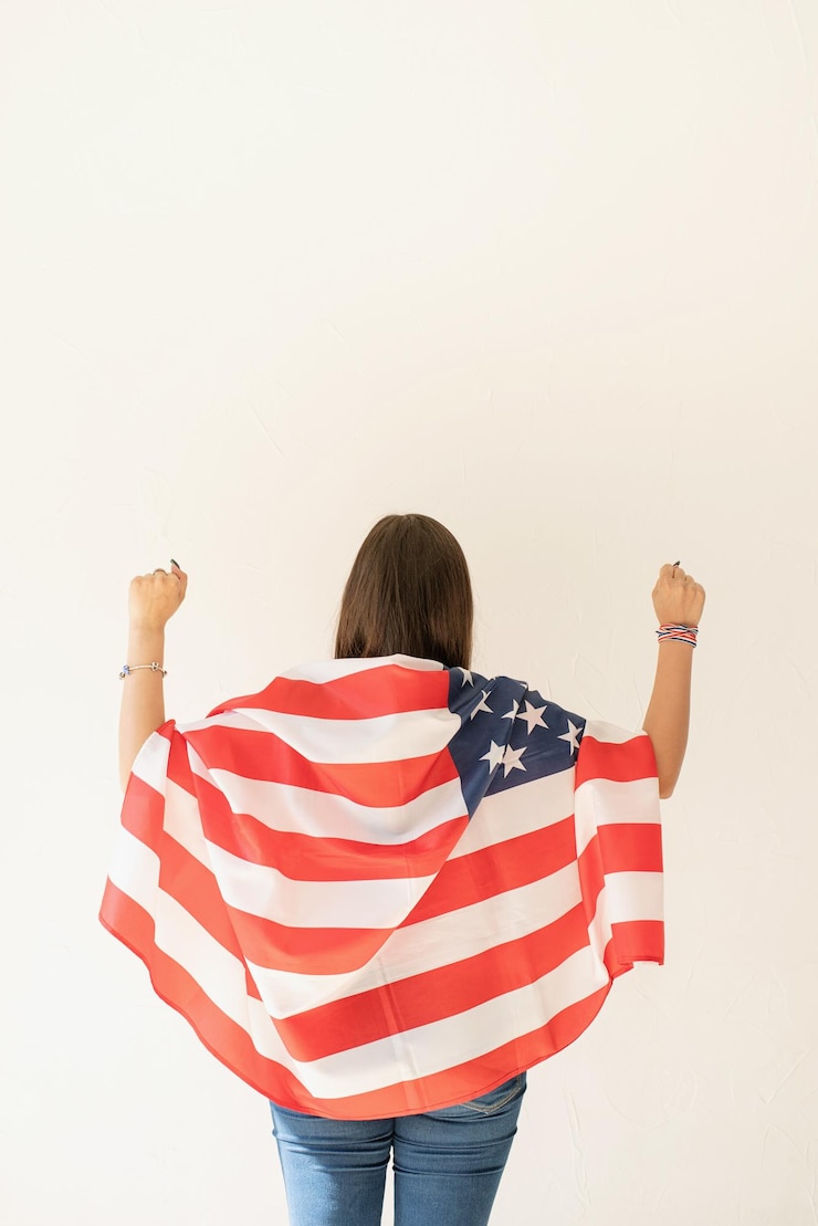 Photo アメリカ国旗を掲げた白い背景に立っている女性の後ろの景色