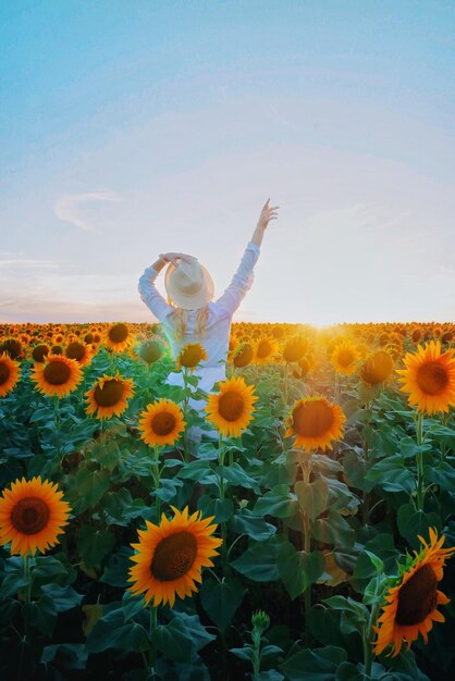 Foto vista posteriore di una donna in piedi tra i girasoli contro il cielo