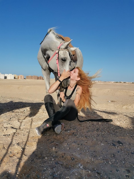 Foto vista posteriore di una donna in piedi sulla spiaggia contro un cielo limpido