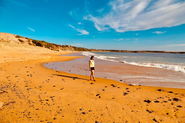 Rear view of woman standing on beach against sky