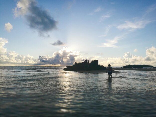 Rear view of woman standing at beach against sky