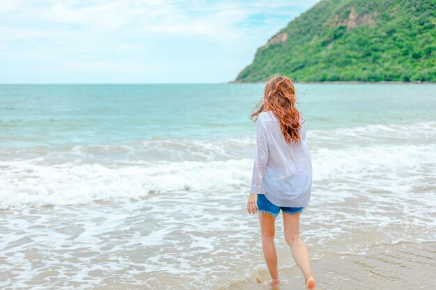 Rear view of woman standing at beach against sky