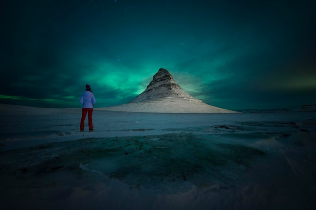 Photo rear view of woman standing on beach by mountain against sky