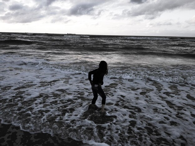 Foto vista posteriore di una donna in piedi sulla spiaggia