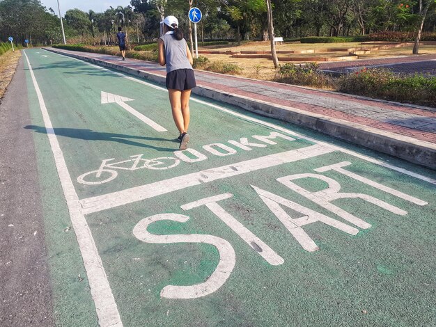 Foto vista posteriore di una donna in piedi sulla pista ciclabile