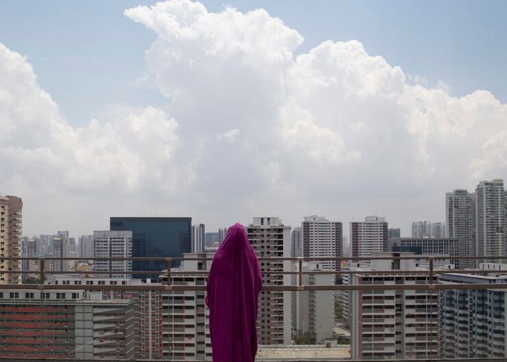 Photo 空に向かって建物のそばに立っている女性の後ろの景色