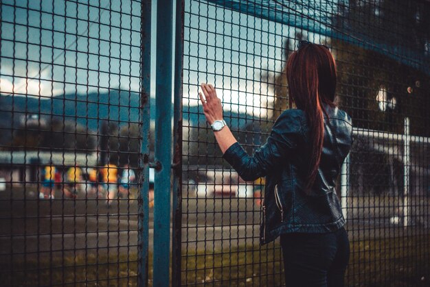 Foto vista posteriore di una donna in piedi vicino alla recinzione