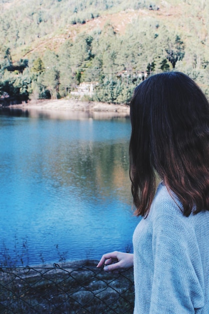 Foto vista posteriore di una donna in piedi vicino al lago nella foresta