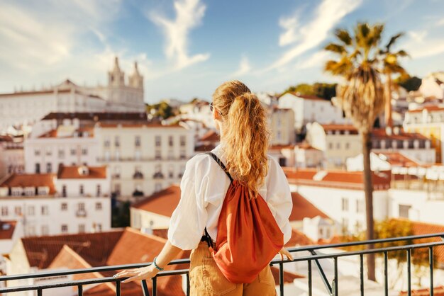 Rear view of woman standing by railing against buildings in city