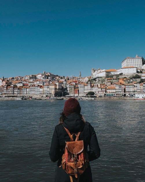 rear view of woman standing by river against clear sky