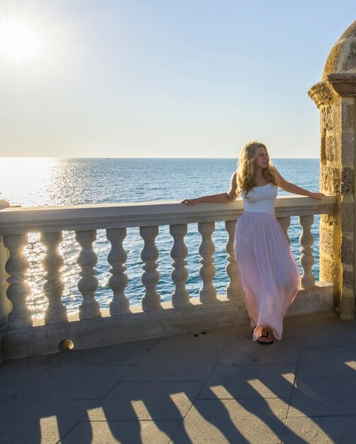 Foto vista posteriore di una donna in piedi sul mare contro il cielo